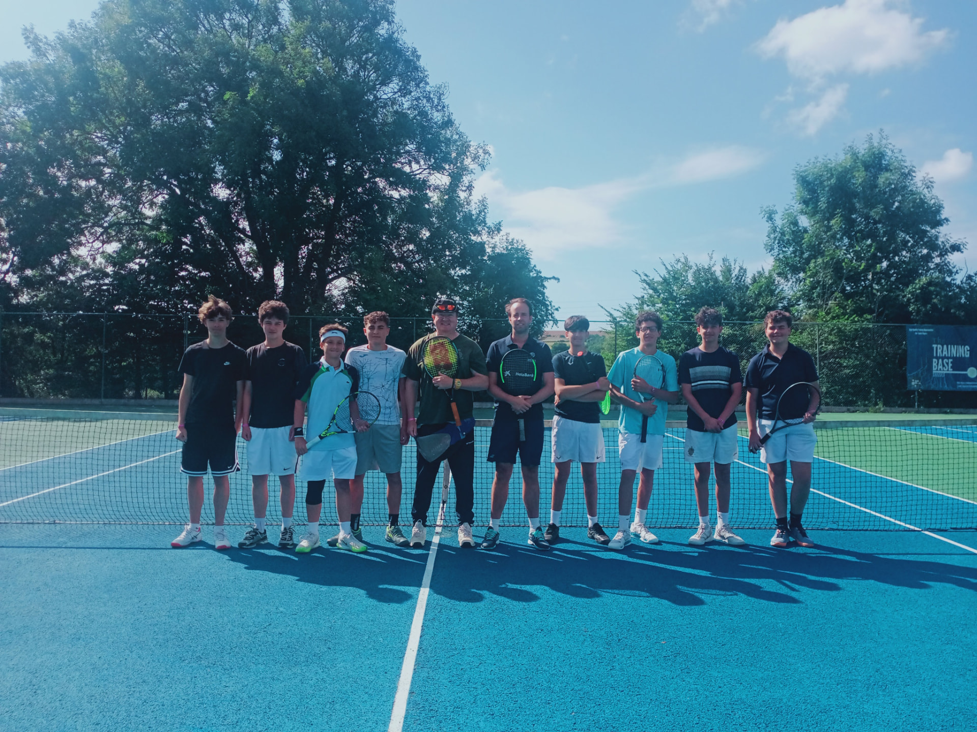 Camp group photo of young tennis players and coaches at the net