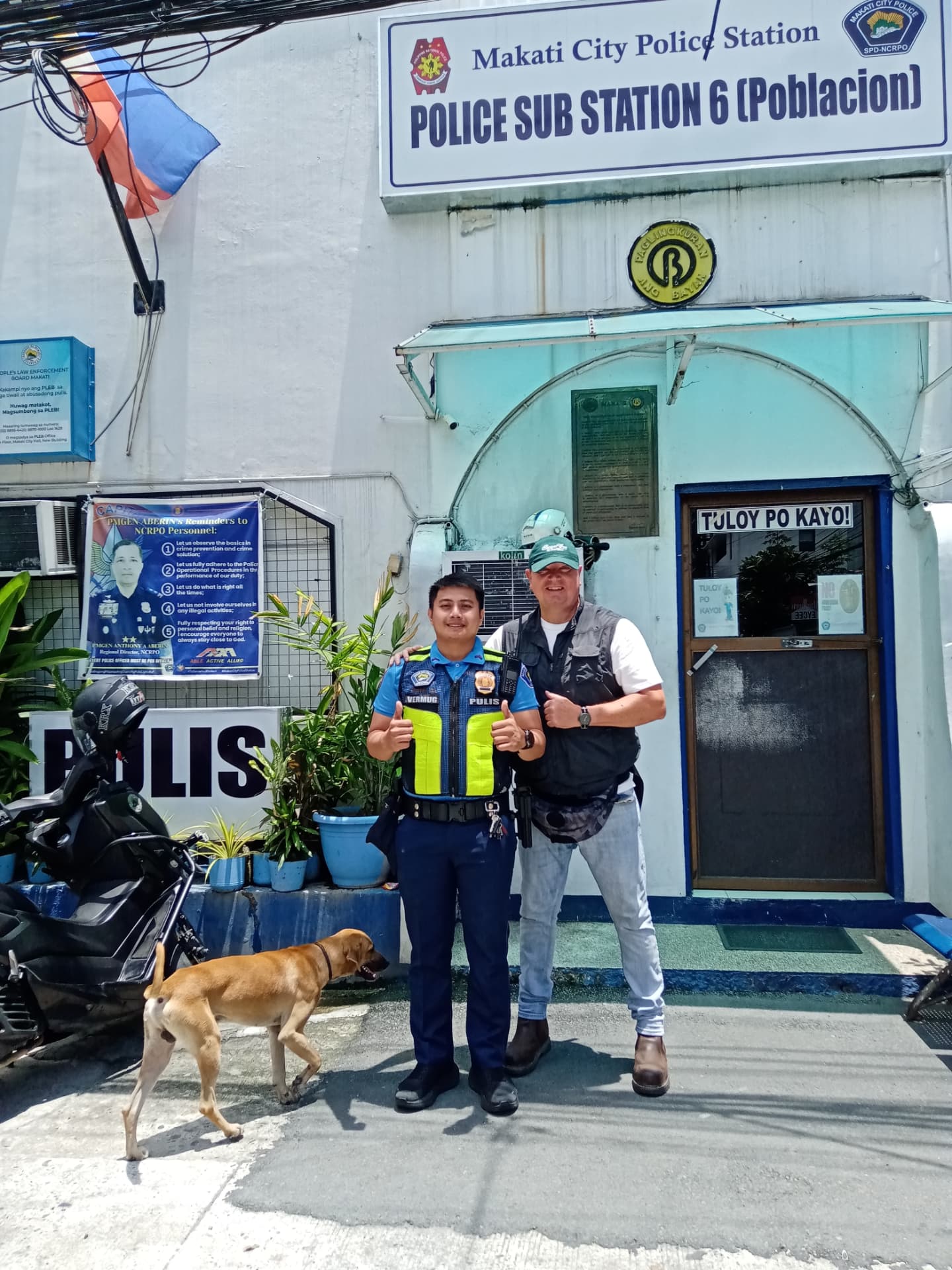 James Corden-Lloyd with a police officer and Joshua the street dog outside Sub-Section 6, Makati City Police Station, Poblacion